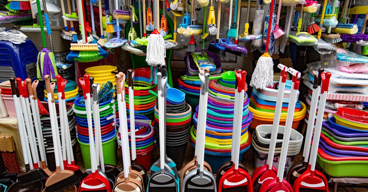 From above various sets of broom and scoop placed in household goods store near colorful basins and bins